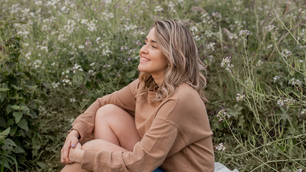 woman in brown long sleeve shirt sitting on green grass during daytime