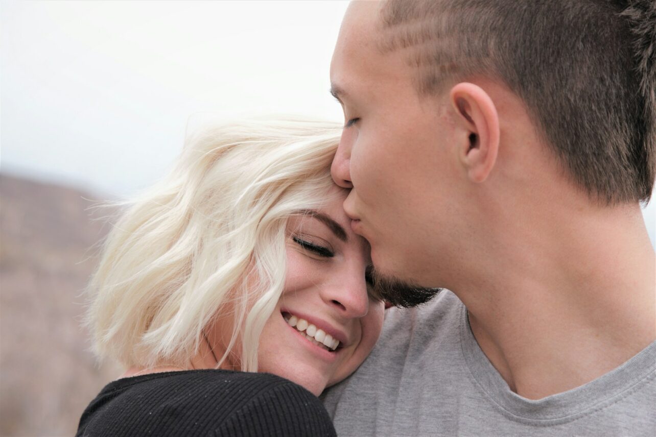 man kissing woman's forehead